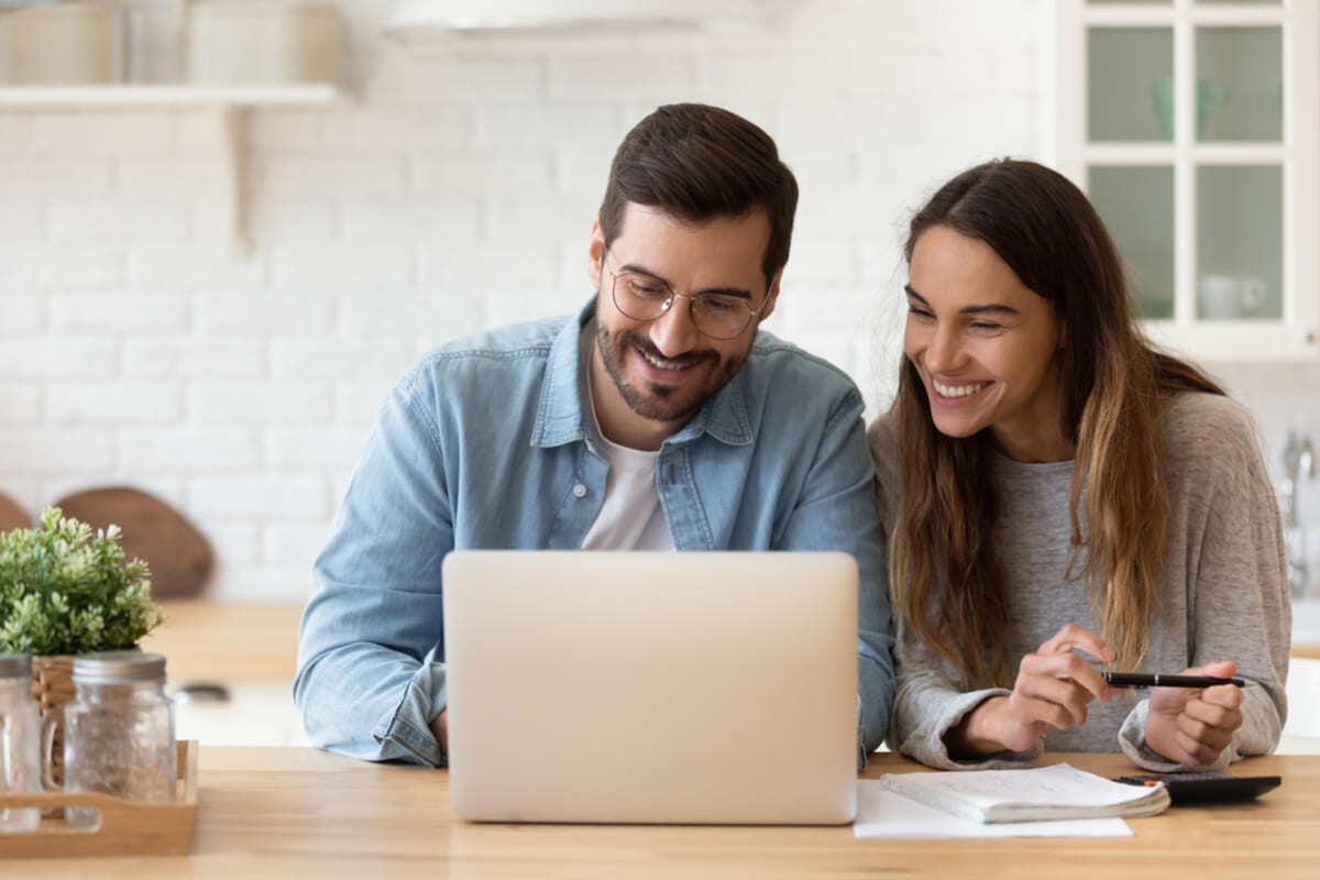 A happy couple looking at a laptop and documents