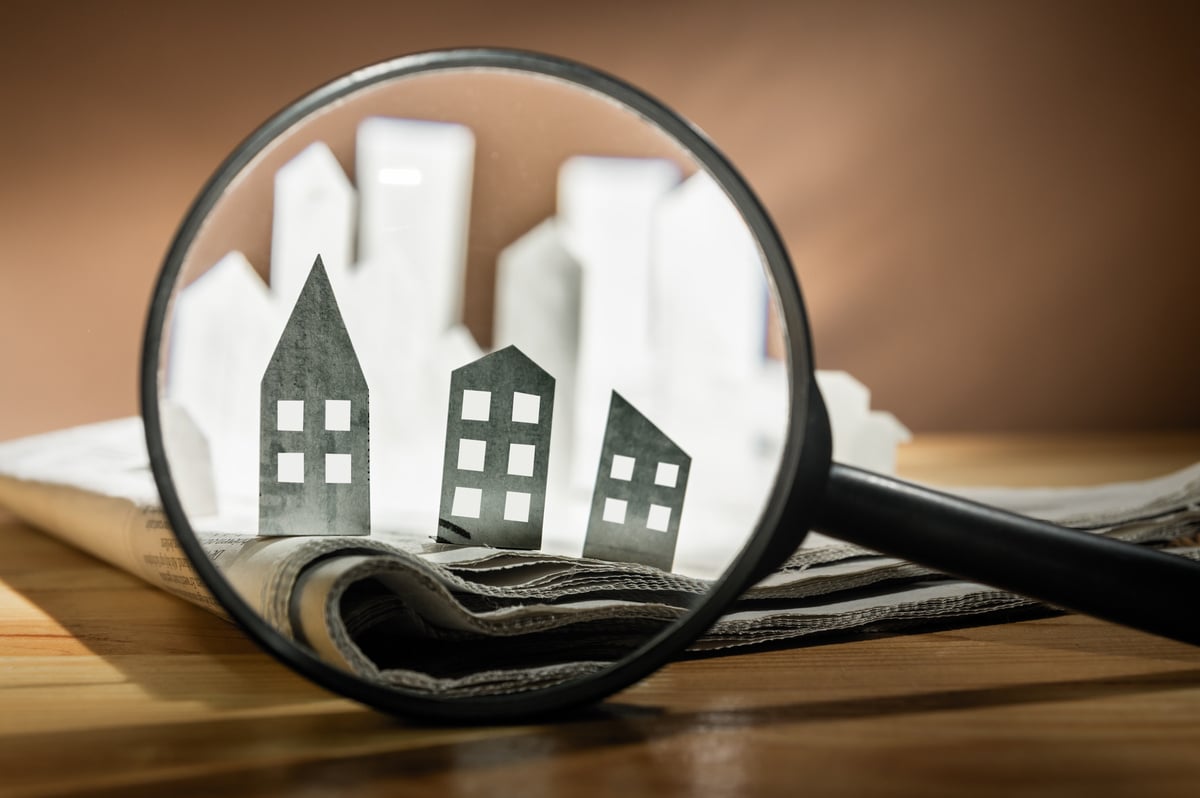 A magnifying glass in front of paper buildings