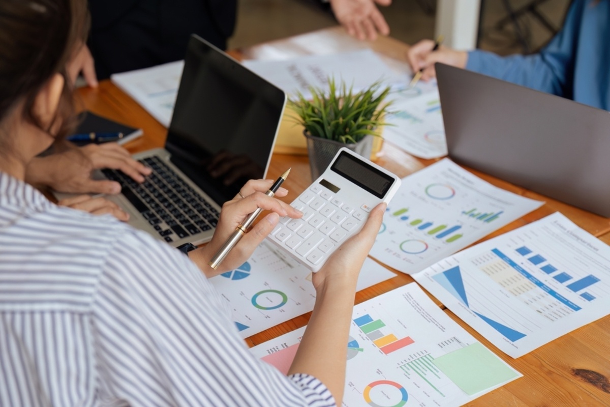 A woman with a calculator looking at data and charts