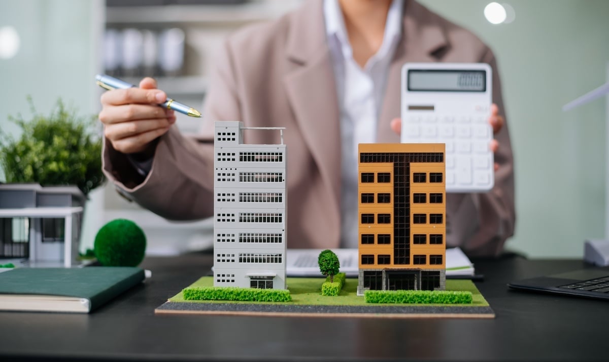 A woman with a calculator next to model commercial buildings