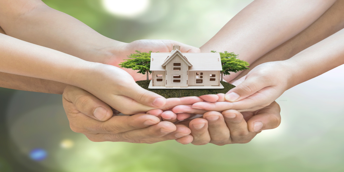 Hands holding a model home and trees