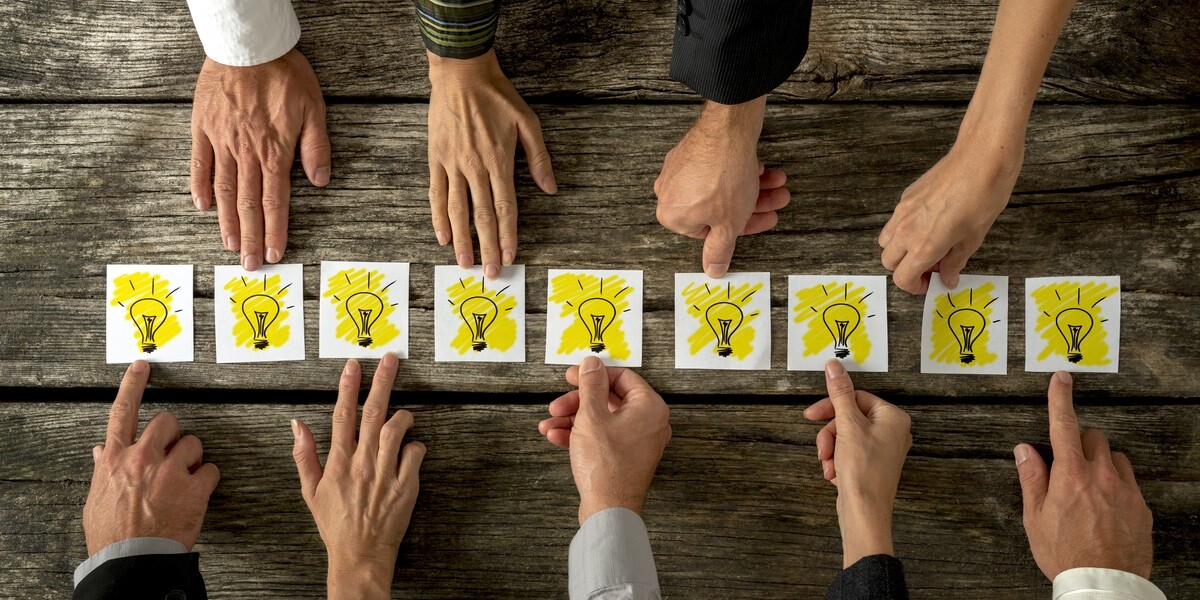 Hands holding paper light bulbs on a wooden table