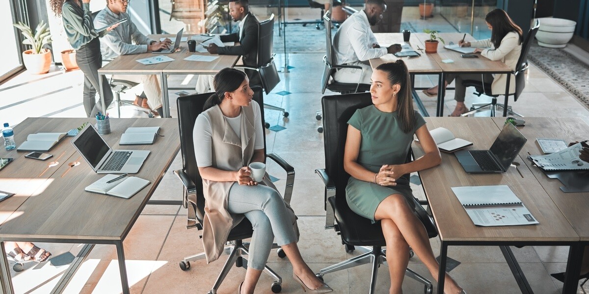 Open office space policy business people having in formal discussion at their desk in a busy, collaboration corporate workplace